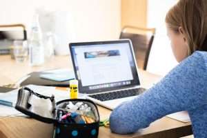 Girl doing homework with a laptop.